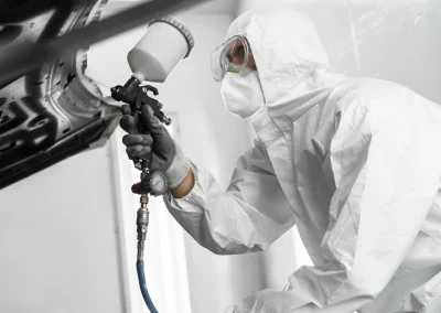 Male painter using gun to paint car in the shop