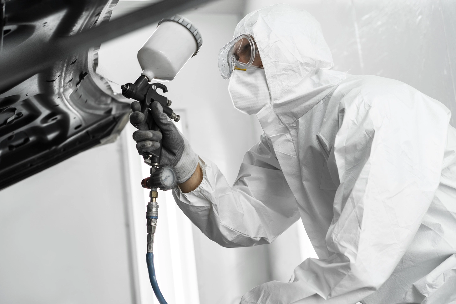 Male painter using gun to paint car in the shop